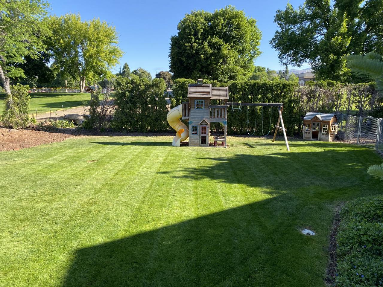 A manicured backyard lawn with a children's play set