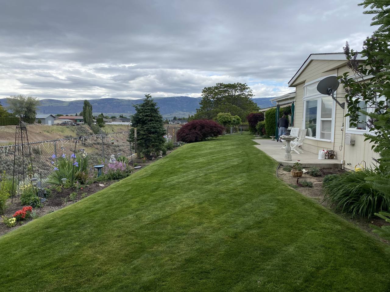 A Twins Landscaping crew member working on a patio and lawn with the Wenatchee Valley in the background